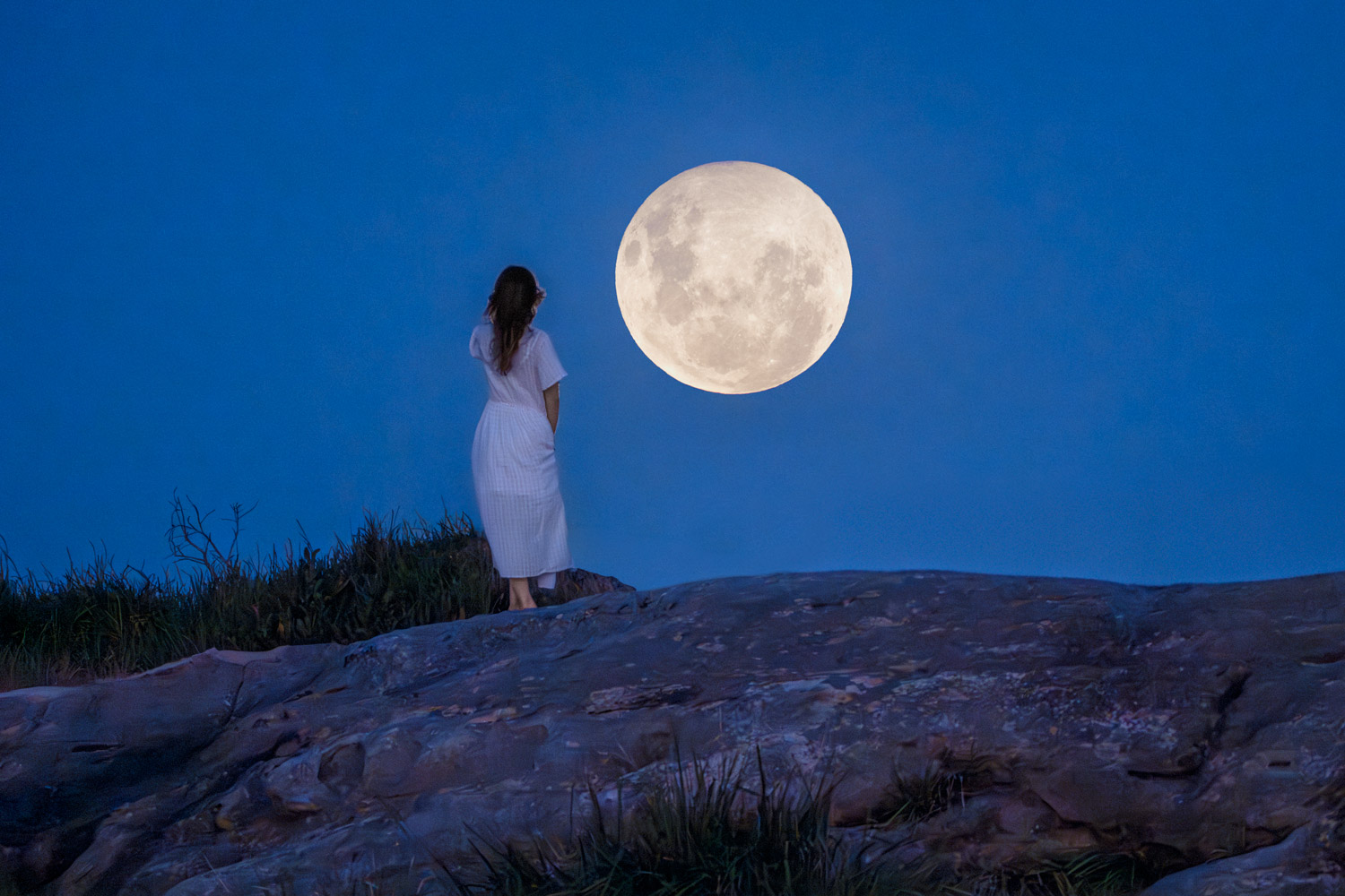 Lady gazing at the Moon in the night sky.